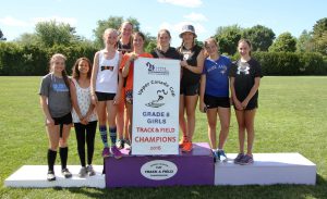 Members of the Seaway District High School Grade 8 girls' team grin at the podium after winning the Grade 8 girls' team banner, preventing a clean sweep by the hosting TISS Pirates. Pictured, left to right, are: Dana Domanko, Madison Michielsen, Erika Jordan, Krista Strader, Harley Heustis, Andi Black, Michaela Mustard, Morgan Hummel, and Reagan Belanger. Missing from the photo are Anu Hunter and Anna Henderson.